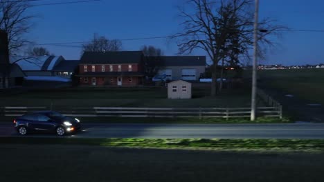 Blue-Tesla-Model-Y-driving-on-rural-USA-road-with-farm