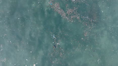 Von-Oben-Nach-Unten-Absteigende-Drohnenaufnahme-Von-Verschmutztem-Wasser-Voller-Plastikmüll-Und-Abgestorbenem-Korallenriff-Im-Türkisfarbenen-Tropischen-Wasser-Des-Balangan-Beach-In-Uluwatu,-Bali,-Indonesien
