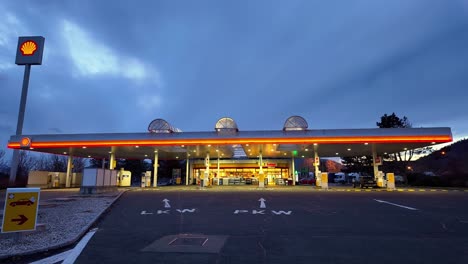 Leere-Beleuchtete-Shell-Tankstelle-Am-Frühen-Abend-Mit-Den-Zapfsäulen-Und-Dem-Shop-Im-Hintergrund