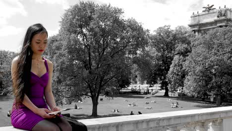 Young-attractive-woman-reading-journal-or-book-on-railing-in-front-of-Burggarten-park-in-Vienna