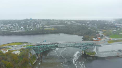 Una-Toma-Aérea-Del-Puente-De-Las-Cataratas-En-Reversa-Con-Autos-Pasando-Por-Encima-En-Un-Día-Nublado