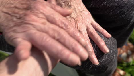 Male-hand-is-grabbing-mature-female-hands-with-Rheumatoid-Arthritis-outdoor