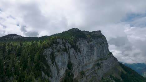 Along-impressive-rock-wall-with-green-pines-Mount-Granier,-French-Alps