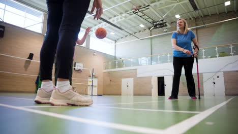 Mujer-Pasando-Una-Pelota-De-Baloncesto-A-Un-Compañero-De-Equipo-Mientras-Usa-Muletas