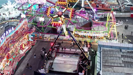 Emocionantes-Atracciones-En-El-Iluminado-Luna-Park-De-Génova,-Situado-Frente-Al-Mar,-Aéreo