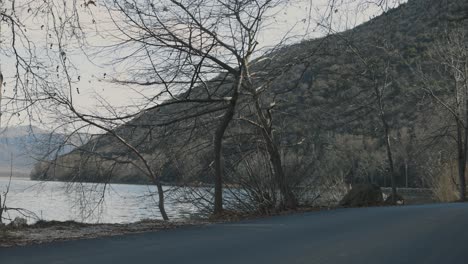 A-static-shot-of-a-dreamy-lake-beach,-forest-mountains-in-the-background,-Europe-Greece,-blue-clear-water,-4K-steady-video