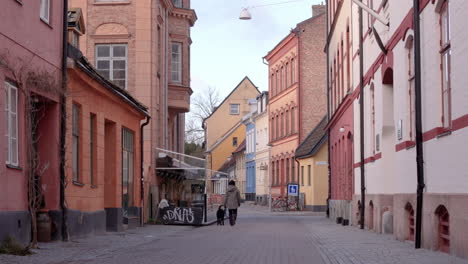 Resident-takes-pet-dog-for-a-walk-down-empty-street-in-Gamla-staden,-Malmo