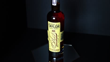 Botella-De-750-Ml-De-Whisky-Bourbon-Puro-De-Kentucky-De-Barril-único-Eh-Taylor-Encima-De-Un-Espejo-Hexagonal-Con-Un-Fondo-Oscuro-Que-Contrasta-Con-La-Botella-De-La-Destilería-Frankfort-Kentucky-Buffalo-Trace