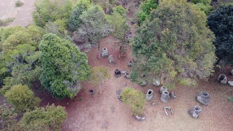 Plain-of-Jars,-aerial-fly-over-scattered-megalithic-structures-in-jungle,-Phonsavanh,-Laos