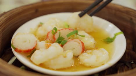 Close-up-of-steamed-shrimp-and-crab-stick-dish,-chopsticks-pick-up-piece