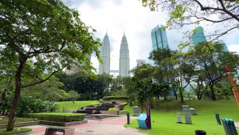 Park-in-Kuala-Lumpur-view-of-tree,-tall-real-estate-buildings-Petronas-Towers