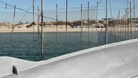 Boot-Schwimmt-Auf-Dem-Meerwasser,-Um-Alte-Traditionelle-Fischernetze-Am-Meer,-Strand,-Meeresabenteuer,-Meeresfrüchte,-Fischen,-Fischer,-Lebensstil-Der-Einheimischen-Auf-Der-Insel-Katar,-Arabische-Kultur-Zu-Besuchen