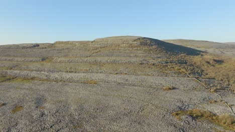 Aerial-establishing-dolly-of-terraced-hill-slope-and-rock-walls-of-the-Burren-Ireland-on-sunny-day