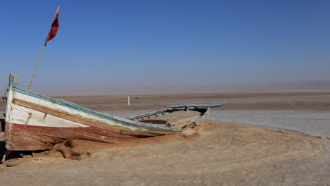 Abandoned-boat-on-the-salt-flats-of-Chott-el-Jerid,-Tunisia-under-clear-blue-sky