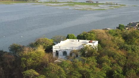 Cámara-De-Teléfono-Con-Vista-Aérea-De-Drones-Avanzando-Mirando-El-Dorso-De-La-Mano-Un-Gran-Lago-Y-Un-Gran-Palacio-En-Medio-Del-Bosque