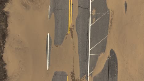 Direct-aerial-over-sand-strewn-road