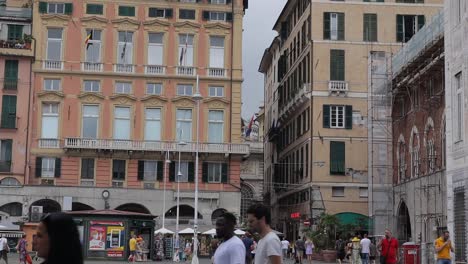 Schwenkaufnahme-Zeigt-Belebte-Piazza-Mit-Vielen-Menschen-Zu-Fuß-In-Alle-Richtungen-In-Der-Traditionellen-Italienischen-Stadt