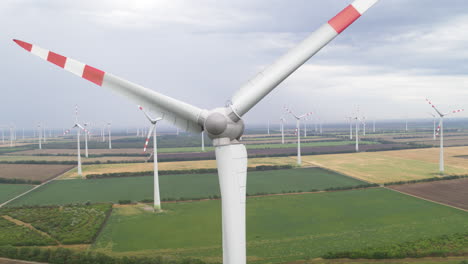 Aerial-of-rotating-Wind-turbine-with-a-backdrop-of-multiple-turbines-on-flat-open-farmland