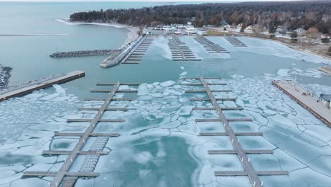 Port-elgin-marina-with-icy-waters-and-docked-boats-in-winter,-aerial-view