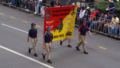 Gente-Marchando-Por-La-Calle-Con-Una-Pancarta-De-La-Asociación-Vietnamita-Del-3er-Regimiento-De-Caballería-El-Día-De-Anzac,-Brisbane,-Australia