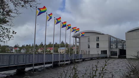 Banderas-Del-Arco-Iris-Del-Orgullo-Del-Progreso-Inclusivo-Intersex-Ondeando-Con-Un-Fuerte-Viento-Junto-Al-Ayuntamiento-De-Reykjavik,-Islandia