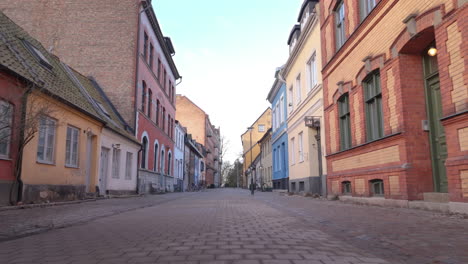 Low-forward-dolly-along-brick-street-in-Gamla-staden-with-colorful-houses,-Malmo