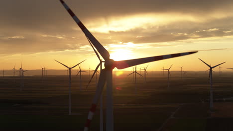 Golden-hour-aerial-of-a-large-Wind-turbine-energy-generation-farm-on-flat-ground