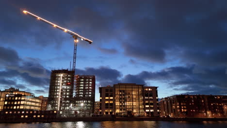 Beleuchteter-Kran-Und-Gebäude-Auf-Der-Baustelle-An-Der-Küste-Von-Malmö,-Drohne