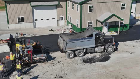 Workers-pave-new-parking-lot-beside-a-spacious-barn-on-a-crisp-autumn-day