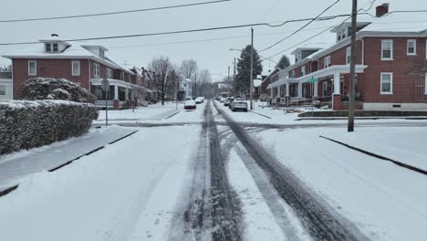 Vuelo-Aéreo-Hacia-Adelante-Sobre-Una-Calle-Húmeda-Y-Nevada-En-Un-Suburbio-Americano