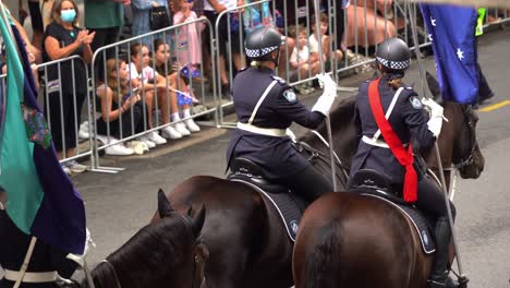 Mounted-Australian-Federal-Police-officers-ride-down-Adelaide-Street,-participating-in-the-Anzac-Day-parade,-honouring-the-memory-of-those-who-served-during-the-war