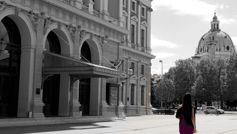 Woman-in-purple-dress-walking-past-historical-buildings-in-black-and-white