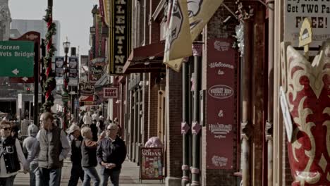 Tourists-on-Broadway-Street-in-Nashville,-Tennessee-during-the-day-with-medium-shot-video-pan-right-to-left-in-slow-motion