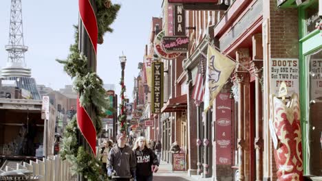 Tourists-on-Broadway-Street-in-Nashville,-Tennessee-during-the-day-with-video-tilting-down