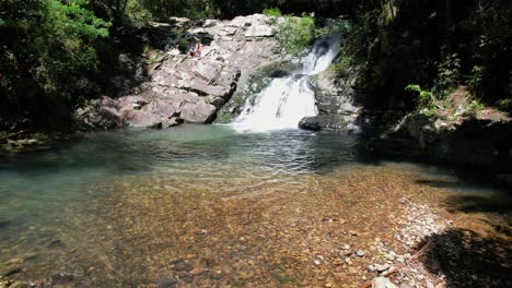 Malerischer-Wasserfall-Mit-Touristen-Im-Currumbin-Valley,-Gold-Coast,-Queensland,-Australien---Drohnenaufnahme