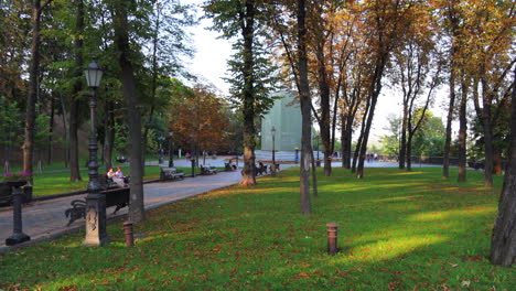 Beautiful-green-park-near-the-Glass-Bridge-in-Kyiv-city-center-Ukraine,-people-enjoying-the-nature,-green-grass-and-trees,-4K-static-shot