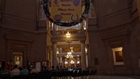 Inside-Indiana-state-capitol-building-in-Indianapolis,-Indiana-with-view-of-dome-tilting-down-to-people-in-a-meeting