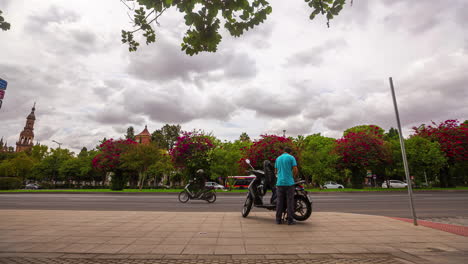 Motociclista-Deteniéndose-En-La-Vibrante-Calle-De-Sevilla-Con-árboles-En-Flor,-Timelapse