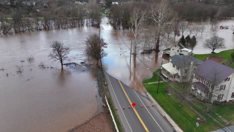 Aerial-view-of-a-flooded-street-with-submerged-trees-and-houses-near-a-clear-roadway