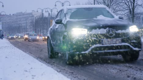 Cars-driving-though-slush-snow-during-snowfall-at-dusk-in-Brussels,-Belgium---Slow-motion