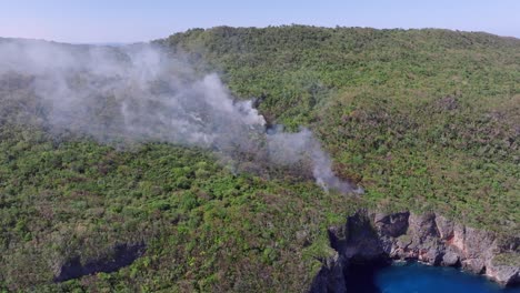 Rainforest-fire,-big-clouds-of-smoke-over-Caribbean-island,-aerial-orbit