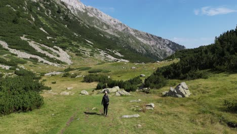 Mujer-Camina-Por-Senderos-De-Montaña-Al-Aire-Libre-En-El-Parque-Nacional-De-Las-Montañas-Pirin,-Bulgaria---Antena-4k