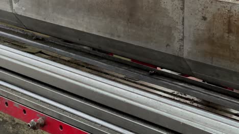 Close-up-shot-of-operator-using-bending-machine-to-make-indentations-in-iron-plate-sheets