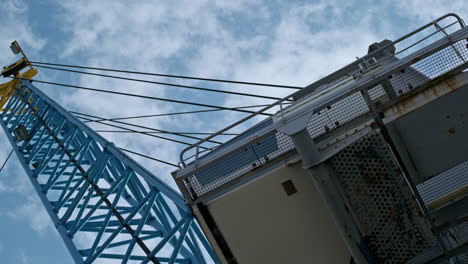 Vista-De-ángulo-Bajo-De-La-Grúa-Industrial-En-El-Puerto-Marítimo-Contra-El-Cielo-Azul