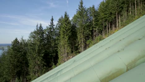 Green-pipeline-running-through-a-forested-area-on-a-clear-day,-angled-shot