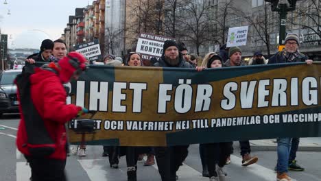 Demonstranten-Gegen-Die-Covid-Verordnung-Marschieren-Mit-Transparenten-Und-Schildern-In-Stockholm