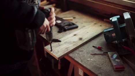 Woodworker-Drilling-Hole-On-Wood-Plank-At-His-Workshop