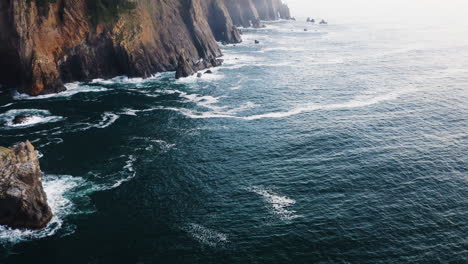 Flight-along-coastline-of-Oregon,-rugged-cliffs-descending-into-Pacific-Ocean