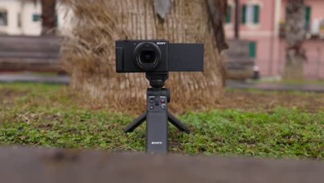 Slider-Aufnahme-Einer-Kompakten-Digitalkamera-Mit-Klappdisplay-Und-Bluetooth-Aufnahmegriff-Auf-Gras