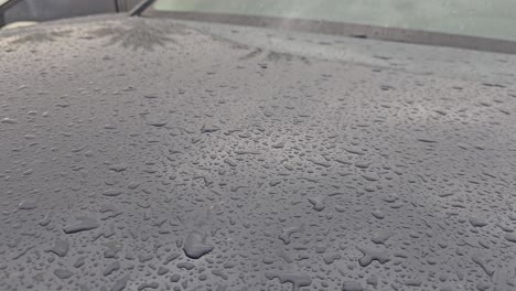 Rainwater-falling-on-the-car,-Raindrops-on-the-car-paint,-Rainwater-drops